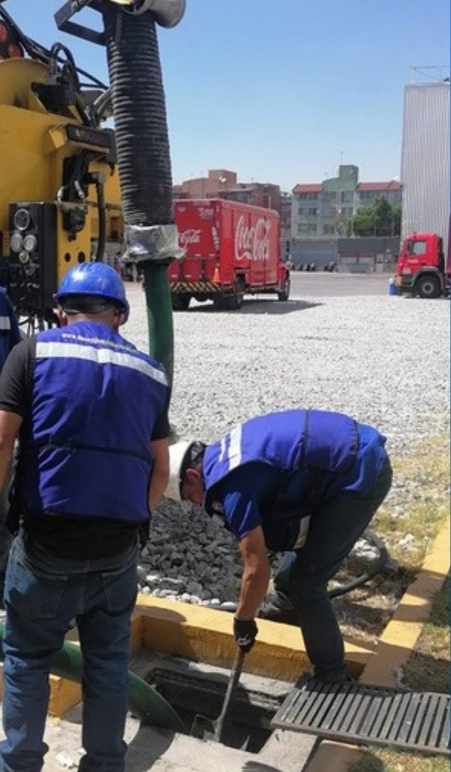 Cuadrilla de DEYSA limpiando un registro pluvial junto a un camión Vactor